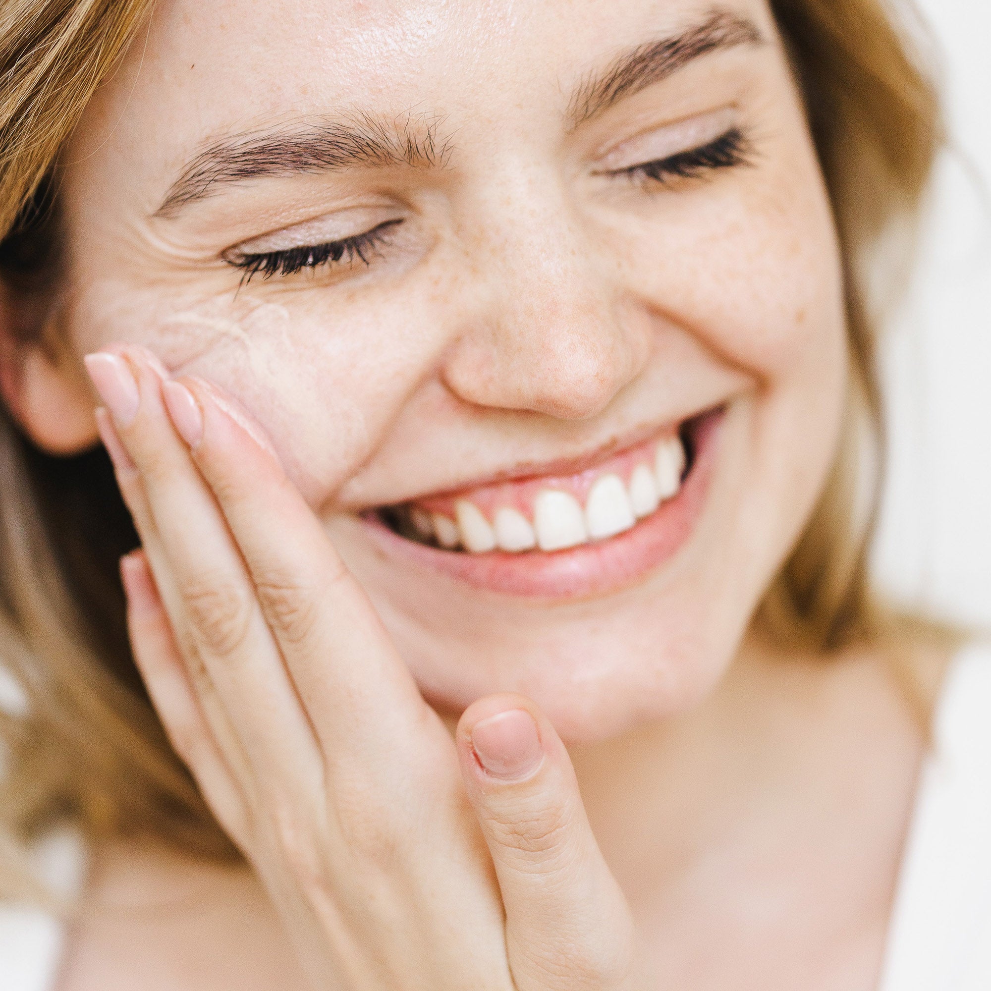 Woman applying tined natural sunscreen to her face. 