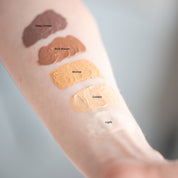 Woman's arm with 5 different shades of LASPA Tinted Matte Sunscreen: Light, Golden, Bronze, Rich Brown, Deep Umber. 